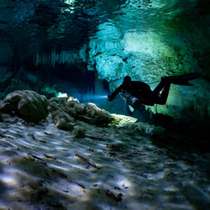 Diver silhouette over a sunlit rippled floor in a shallow cavern, Quintana Roo, Mexico