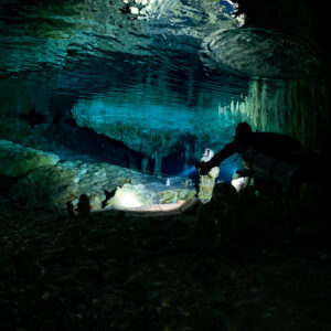 Diver silhouette in a dark cavern under a mirror-like surface, Quintana Roo, Mexico