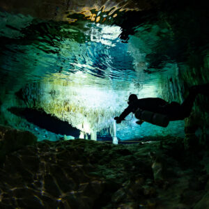 Diver silhouette before a bright cavern zone with reflected surface, Quintana Roo, Mexico