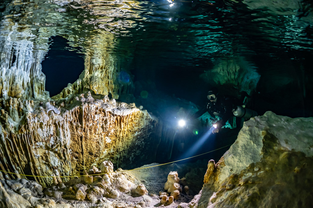 Plongeurs éclairant une caverne de rideaux de calcite dorés et de piliers, Quintana Roo, Mexique