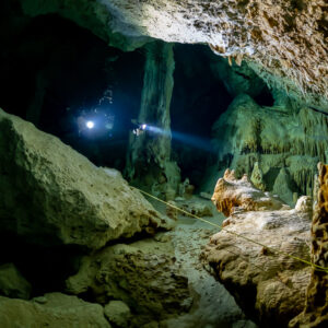 Two divers beaming torches between fallen blocks and stalagmites, Quintana Roo, Mexico