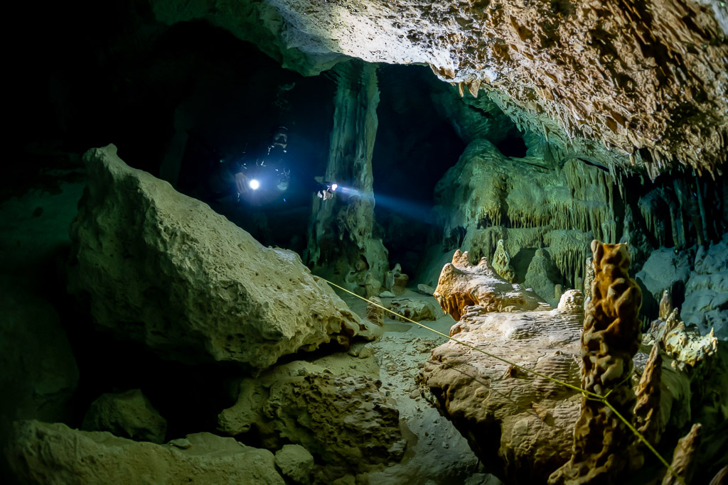 Deux plongeurs éclairant entre des blocs effondrés et des stalagmites, Quintana Roo, Mexique
