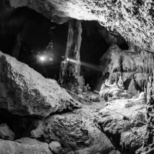 Black and white divers with torches among fallen blocks and stalagmites, Quintana Roo, Mexico