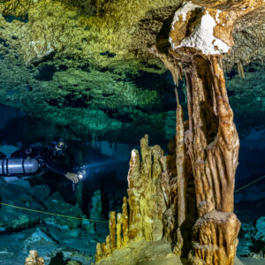Sidemount diver beside a tall flowstone column and stalagmites, Quintana Roo, Mexico