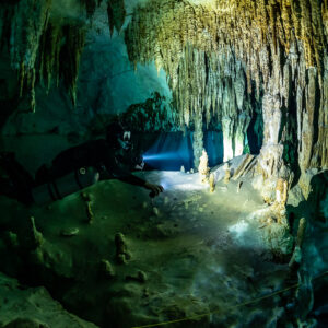 Sidemount diver beaming into a passage lined with stalactites, Quintana Roo, Mexico