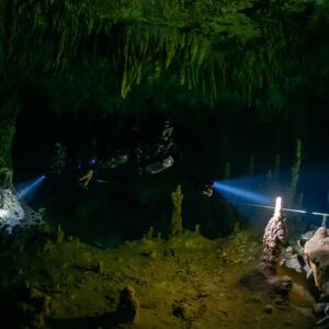 Two divers with torches along a guideline in a dark decorated chamber, Quintana Roo, Mexico