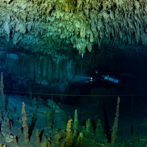Distant diver in a wide chamber of thin stalagmites and stalactites, Quintana Roo, Mexico