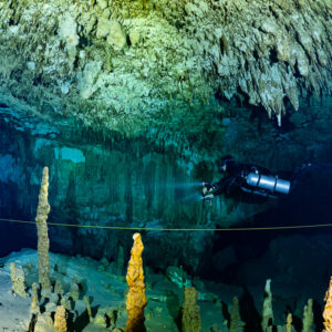 Sidemount diver beside a guideline among slender stalagmites, Quintana Roo, Mexico