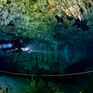 Sidemount diver lighting a guideline under a dense stalactite ceiling, Quintana Roo, Mexico