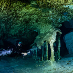 Sidemount diver passing a dripping flowstone formation, Quintana Roo, Mexico
