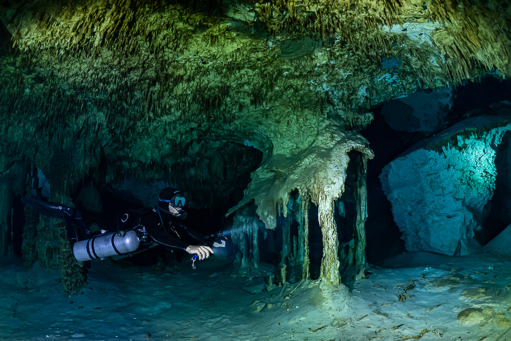 Plongeur en sidemount passant devant une coulée de calcite en draperie, Quintana Roo, Mexique