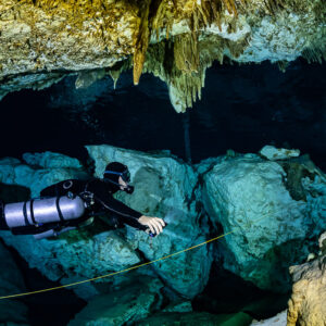Sidemount diver following a guideline between pale boulders, Quintana Roo, Mexico