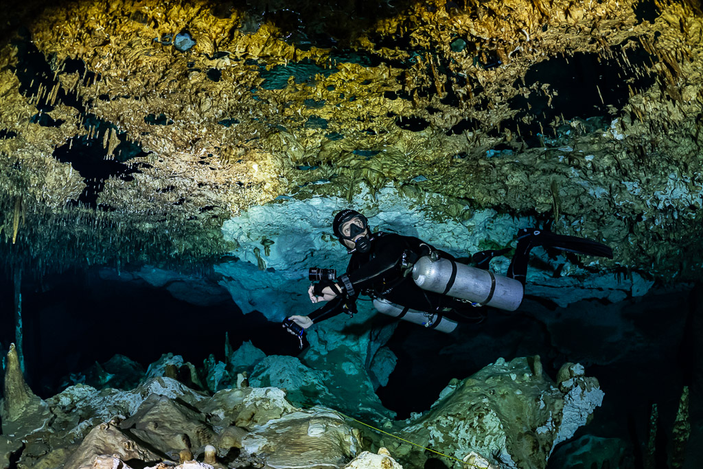 Plongeur en sidemount avec appareil photo parmi les concrétions sous la voûte d’une grotte, Quintana Roo, Mexique