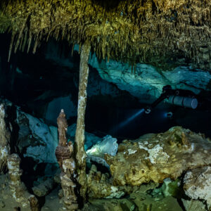 Sidemount diver behind a slender column and colorful stalagmites, Quintana Roo, Mexico
