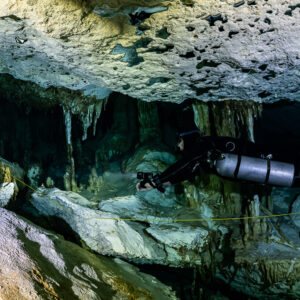 Sidemount diver under a pitted limestone ceiling with short stalactites, Quintana Roo, Mexico