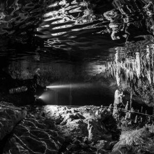 Black and white diver under rippled surface reflections and stalactites, Quintana Roo, Mexico
