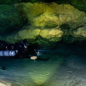 Sidemount diver below a bulging golden flowstone ceiling, Quintana Roo, Mexico