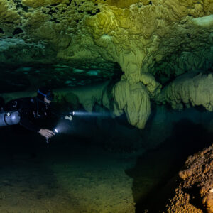 Sidemount diver near a draped formation and an orange stalagmite, Quintana Roo, Mexico