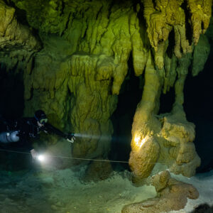Sidemount diver lighting a golden column along a guideline, Quintana Roo, Mexico