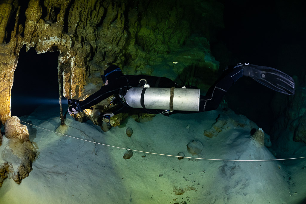 Plongeur en sidemount allongé le long d’un fil d’Ariane au-dessus du sable clair, Quintana Roo, Mexique