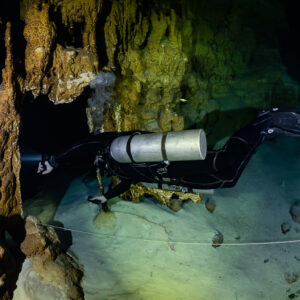 Sidemount diver near a golden column, slightly wider framing, Quintana Roo, Mexico