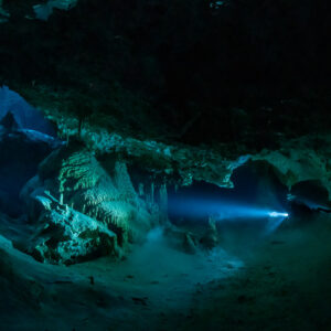 Cave diver's distant torch beam in a wide stalactite-lined chamber, Quintana Roo, Mexico