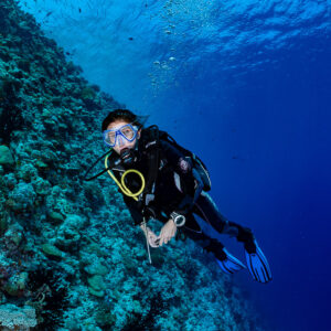 Diver gliding down a reef slope toward the camera, Golden Wall, Maldives