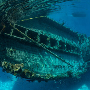 Sunken boat wreck lying on its side in shallow turquoise water, Maldives