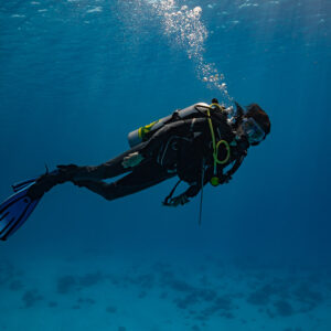 Woman diver swimming in green-blue water above a sandy bottom, Devana Kandu, Maldives