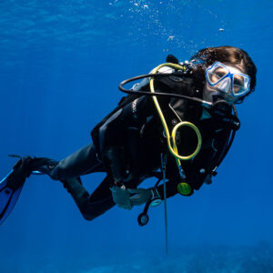 Woman diver in close-up swimming in blue water with bubbles, Devana Kandu, Maldives