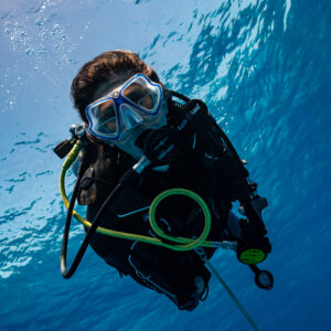 Woman diver portrait under the rippled surface, vertical framing, Devana Kandu, Maldives