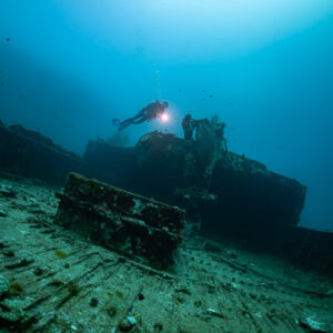 Diver with torch exploring the deck of a shipwreck, wide view, Kuda Giri Wreck, Maldives