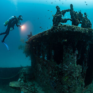 Diver lighting the superstructure of a coral-covered wreck, Kuda Giri Wreck, Maldives