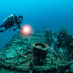 Diver with torch above the bow and bollard of a wreck, Kuda Giri Wreck, Maldives