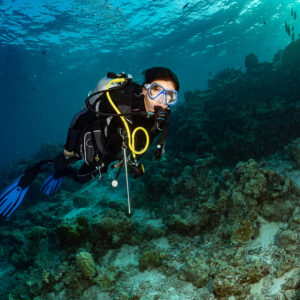 Woman diver close-up swimming over a shallow reef ledge, Kuda Giri Wreck, Maldives