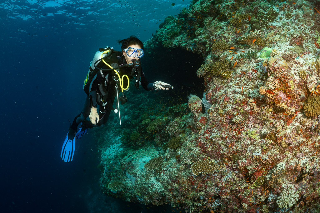 Plongeuse face à l’objectif près de l’entrée d’une grotte récifale, épave de Kuda Giri, Maldives