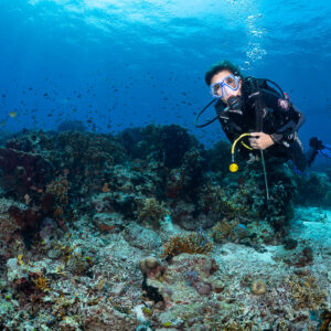 Woman diver facing camera close to a coral reef, Komodo, Indonesia