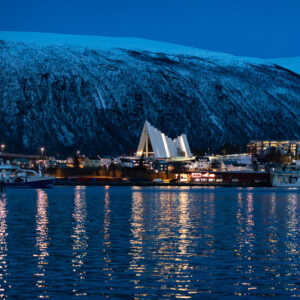 Arctic Cathedral and waterfront lights reflected in the sea at blue hour, Tromsø, Troms, Norway