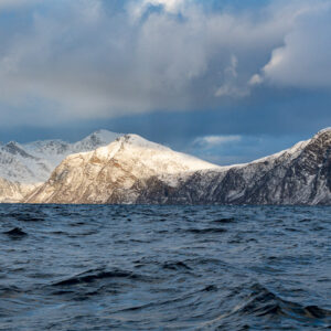 Snowy peaks catching soft light above rippled fjord water, wide view, Kvænangen, Troms, Norway