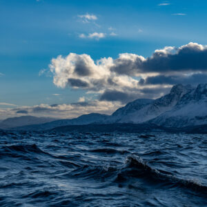 Vagues du fjord en contre-plongée, crête enneigée découpée et nuages blancs, Kvænangen, Troms, Norvège