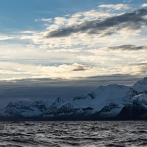 Snowy mountains under streaked clouds above a dark choppy fjord, Kvænangen, Troms, Norway