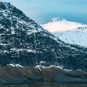 Steep snowy mountain above a coastal hamlet, vertical frame, Kvænangen, Troms, Norway