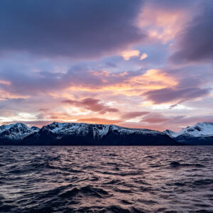 Purple and orange clouds over a snowy ridge and rippled fjord, Kvænangen, Troms, Norway