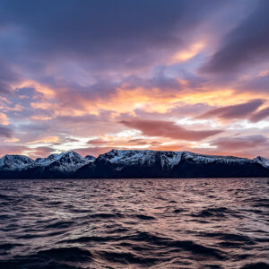 Pastel dusk clouds above snow-covered mountains across the fjord, Kvænangen, Troms, Norway