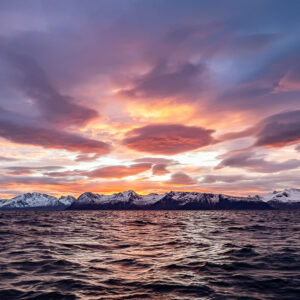 Vaste ciel crépusculaire aux nuages violets au-dessus d’une côte enneigée lointaine, Kvænangen, Troms, Norvège