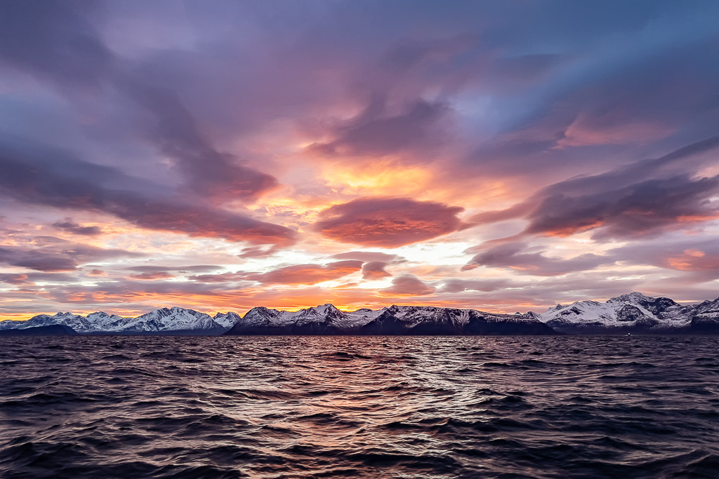 Vaste ciel crépusculaire aux nuages violets au-dessus d’une côte enneigée lointaine, Kvænangen, Troms, Norvège