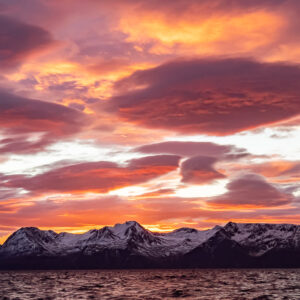 Blazing orange and purple sky over a snowy mountain chain, Kvænangen, Troms, Norway