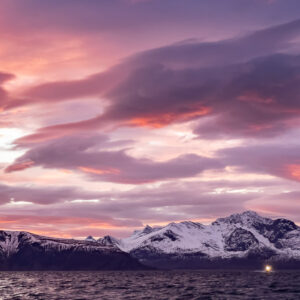 Lenticular-like pink clouds over snowy mountains with a boat light, Kvænangen, Troms, Norway