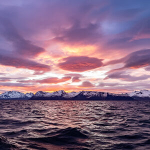 Violet dusk clouds over a thin line of snowy mountains and rippled sea, Kvænangen, Troms, Norway