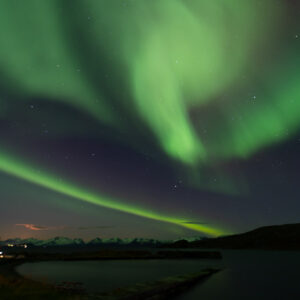 Aurore boréale verte tourbillonnant au-dessus d’un rivage sombre du fjord, cadrage vertical, Seglvik, Troms, Norvège